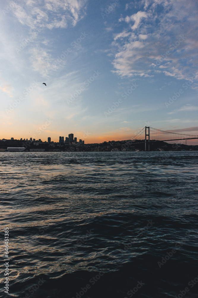 View of bosphorus strait water at sunset with low light and bridge with skyline