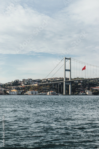 View of bosphorus strait water at sunset with beautiful light and bridge with skyline and huge flag © Radu