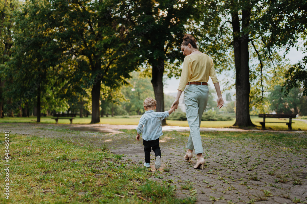 Rear view of mother with little son on together walk after work day. Rear view of mother with little son on together walk after work day.