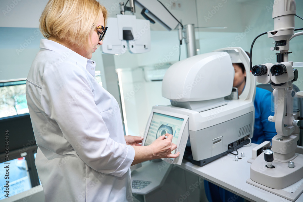 Concentrated oculist conducting automated objective refraction in client Concentrated oculist conducting automated objective refraction in client