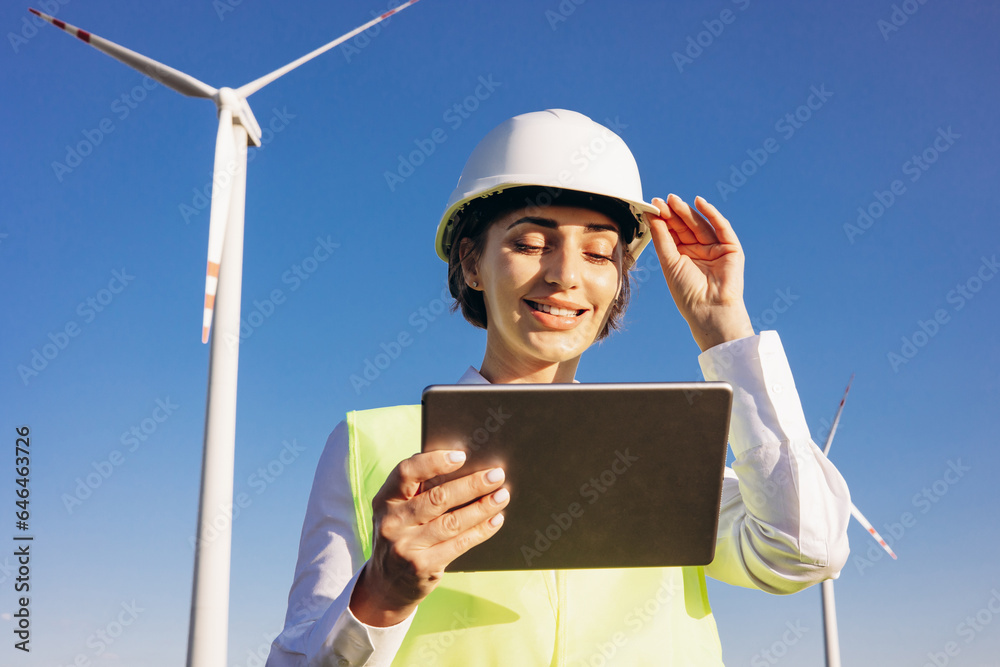 Woman working on tablet, controlling functioning of wind turbines Woman working on tablet, controlling functioning of wind turbines