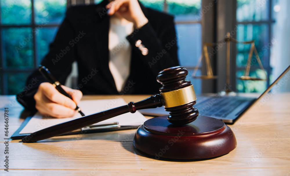 Justice and law concept.Male judge in a courtroom with the gavel, working with, computer and docking keyboard, eyeglasses, on table in morning light Justice and law concept.Male judge in a courtroom with the gavel, working with, computer and docking keyboard, eyeglasses, on table in morning light