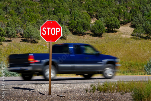 Bright Red Stop Sign with Blurry Blurred Moving Car or Truck Speeding Past photo