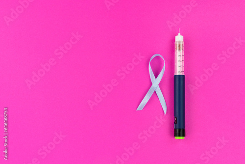 Insulin syringe pen with a needle to fight diabetes and a blue ribbon on a bright background
