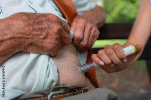 Nurse injecting insulin in belly of diabetic senior patient, using insulin pen. Senior healthcare and diabetes in older people. 
