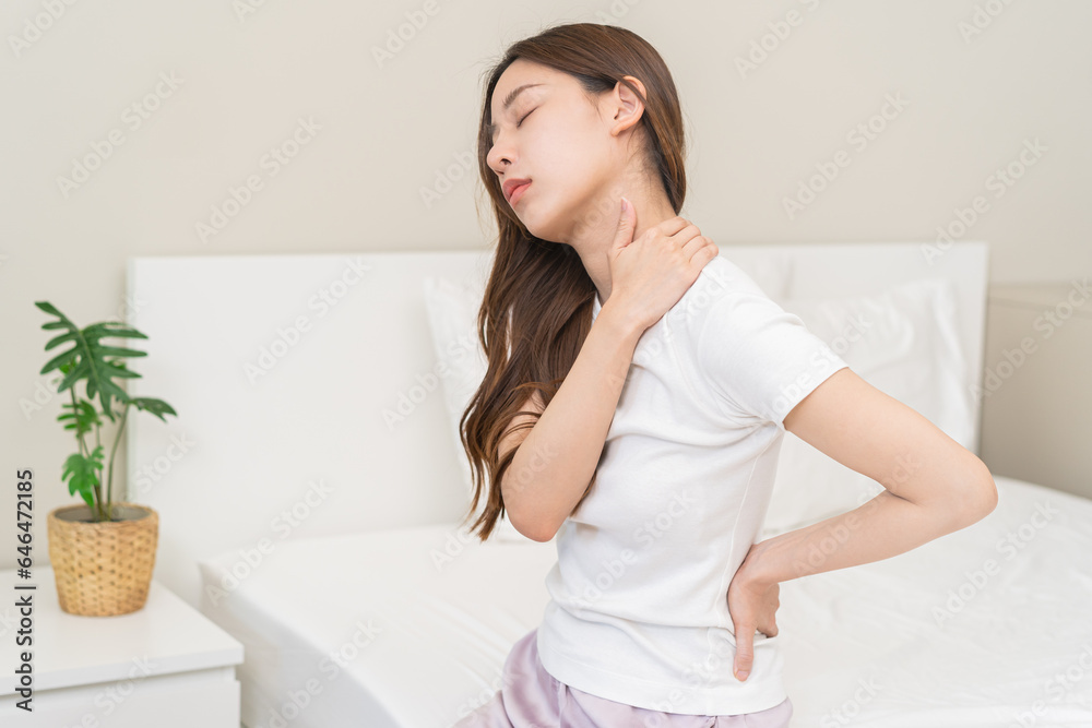 Pain body muscles stiff problem, asian young woman painful with back, neck ache from work hand holding massaging rubbing shoulder hurt, sore sitting on bed in room at home. Health care and medicine. Pain body muscles stiff problem, asian young woman painful with back, neck ache from work hand holding massaging rubbing shoulder hurt, sore sitting on bed in room at home. Health care and medicine.
