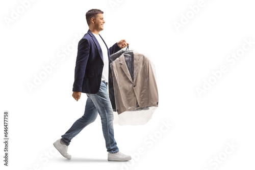 Full length profile shot of a man carrying suit on a hanger with a plastic dry cleaning bag