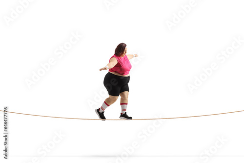 Full length profile shot of a corpulent female trying to walk on a tightrope