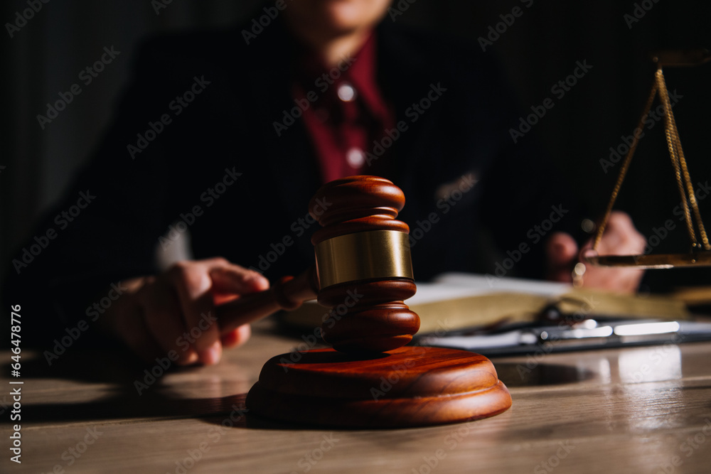 Justice and law concept.Male judge in a courtroom with the gavel, working with, computer and docking keyboard, eyeglasses, on table in morning light Justice and law concept.Male judge in a courtroom with the gavel, working with, computer and docking keyboard, eyeglasses, on table in morning light