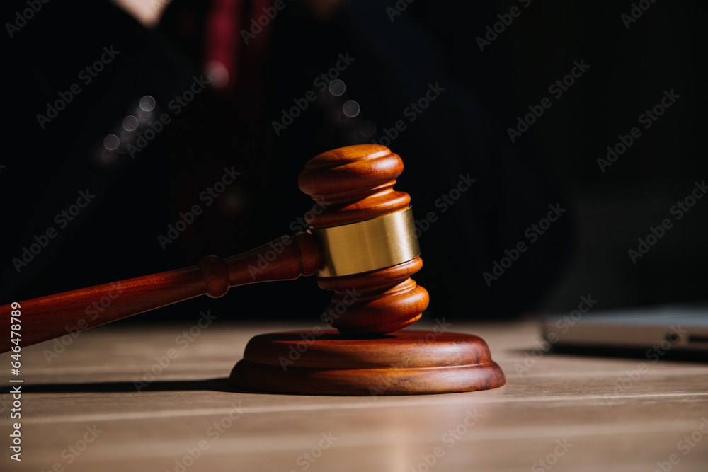 Justice and law concept.Male judge in a courtroom with the gavel, working with, computer and docking keyboard, eyeglasses, on table in morning light Justice and law concept.Male judge in a courtroom with the gavel, working with, computer and docking keyboard, eyeglasses, on table in morning light
