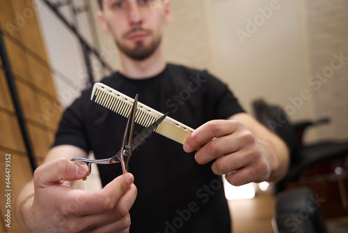 Barber holds special scissors and a comb in his hands