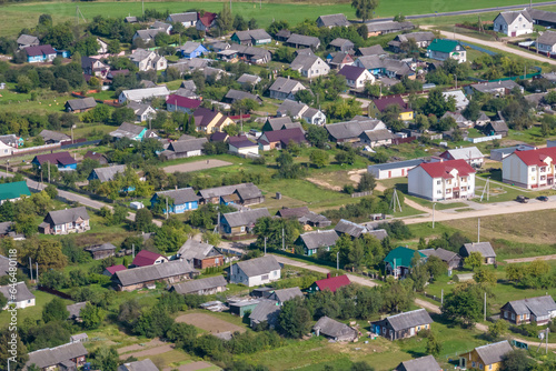 panoramic aerial view of eco village with wooden houses  gravel road  gardens and orchards