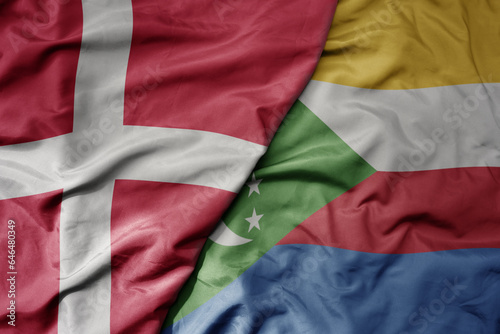 big waving national colorful flag of denmark and national flag of comoros .
