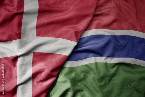 big waving national colorful flag of denmark and national flag of gambia .