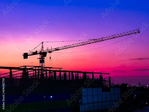 Large construction site including several cranes background Steel frame structure on a building sunset