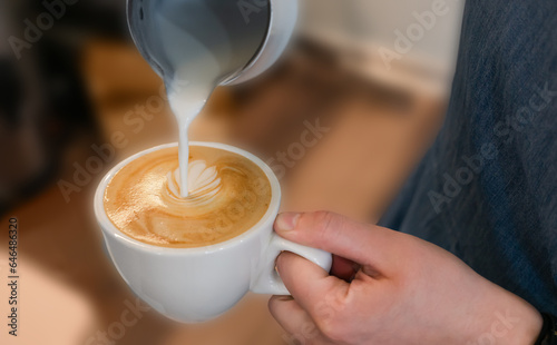 Barista girl pours freshly milk in to cappuccino or latte. Close-up. Selective focus.