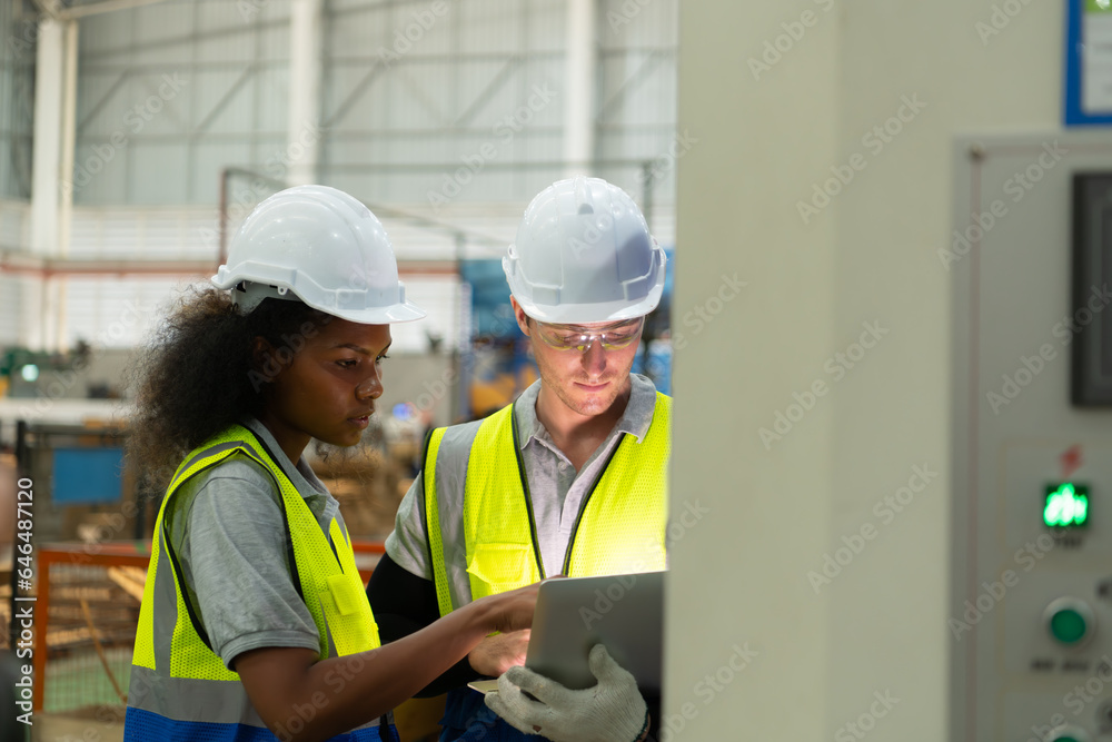 Portrait of two female engineers using laptop while standing in factory, To check the operation of the machine's circuit board. Portrait of two female engineers using laptop while standing in factory, To check the operation of the machine's circuit board.