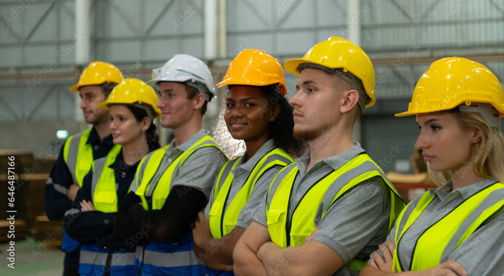 Group of diverse factory workers standing in a row and young female in center looking at camera Group of diverse factory workers standing in a row and young female in center looking at camera
