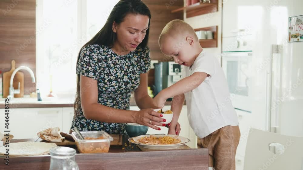 Happy mom and son kid preparing tortillas for breakfast, cooking in home kitchen together Happy mom and son kid preparing tortillas for breakfast, cooking in home kitchen together