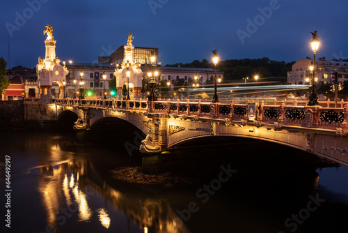 The elegant Maria Cristina bridge over the Urumea river built in the 20th century with its obelisks and the sculptures that crown them in the city of San Sebastian at night, Donostia, Spain