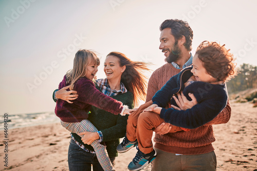 Young happy family walking on a sandy beach during winter photo