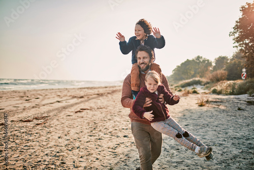 Happy young father taking his kids for a walk on a sandy beach during winter