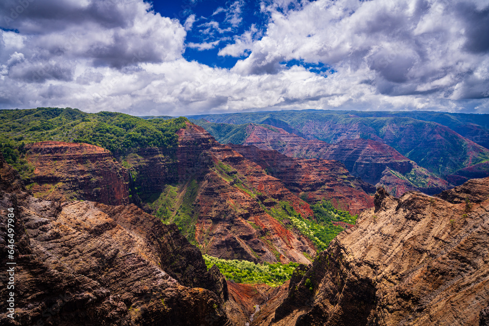 Lights and shadow from sunlight illuminate the dramatic colors and shapes of the cliffs of Waimea Canyon on Hawaiian island of Kauai