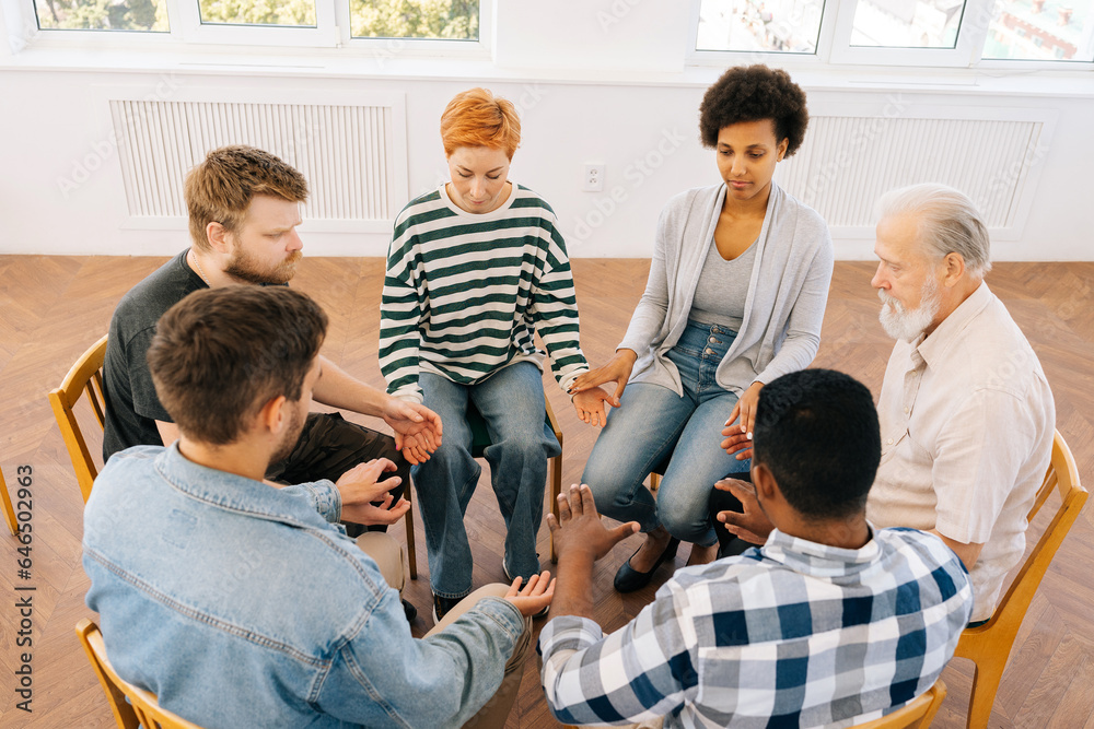 Shooting from above of diverse men and women sitting in circle during group therapy, supporting each other, holding hands. Concept of mental health, psychotherapy, social issues, support, assistant. Shooting from above of diverse men and women sitting in circle during group therapy, supporting each other, holding hands. Concept of mental health, psychotherapy, social issues, support, assistant.