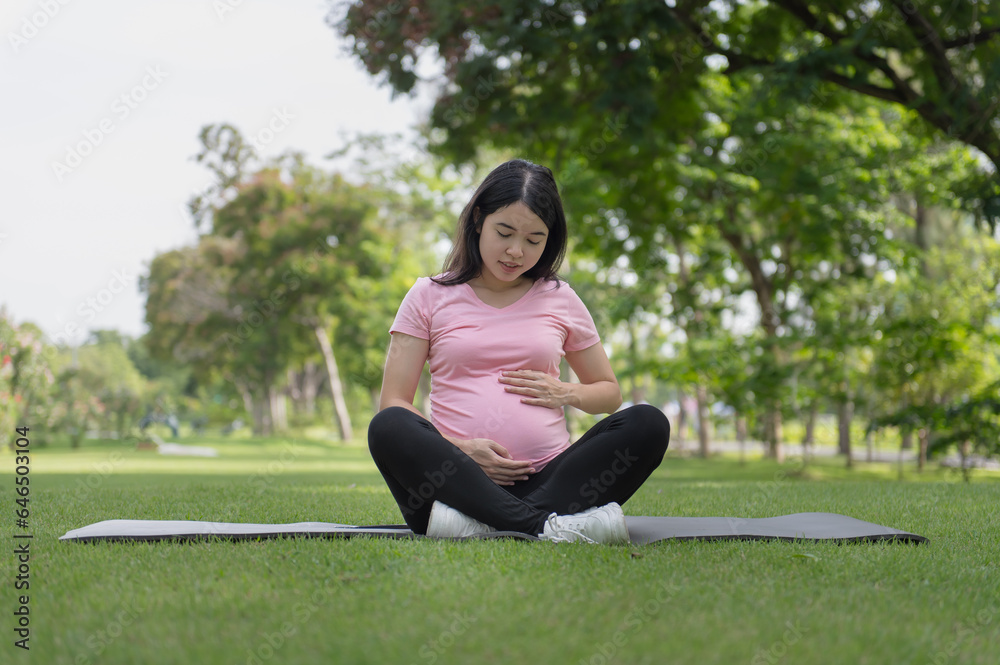 Asian mother's hand is stroking her pregnant belly Asian mother's hand is stroking her pregnant belly