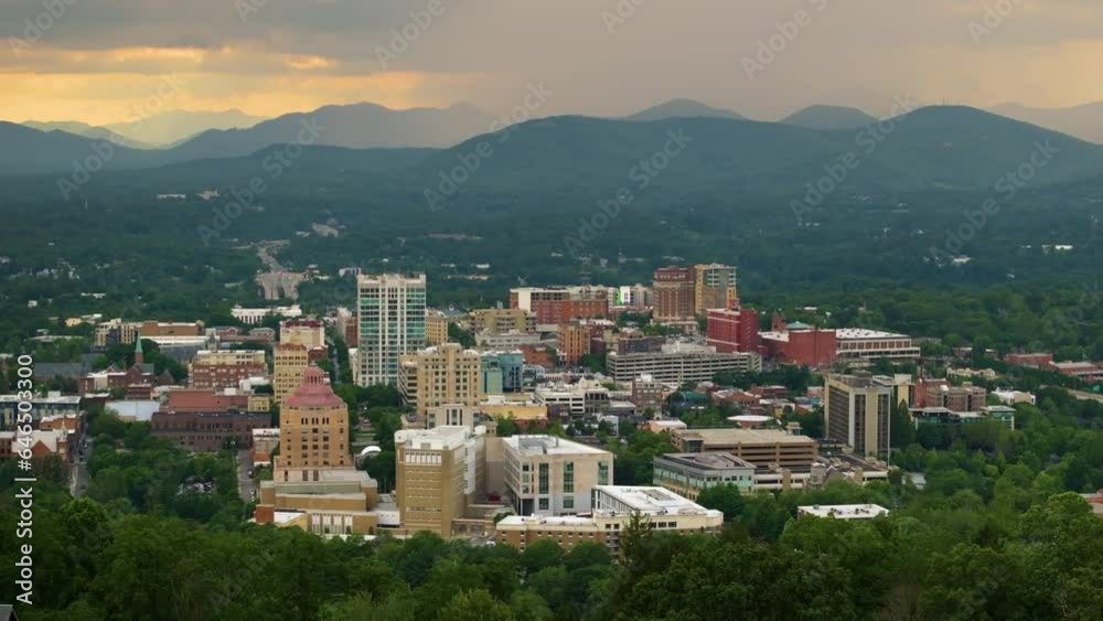 Asheville city in North Carolina at sunset. Downtown architecture with high buildings and Appalachian mountain hills in distance at bright evening. USA travel destination Asheville city in North Carolina at sunset. Downtown architecture with high buildings and Appalachian mountain hills in distance at bright evening. USA travel destination