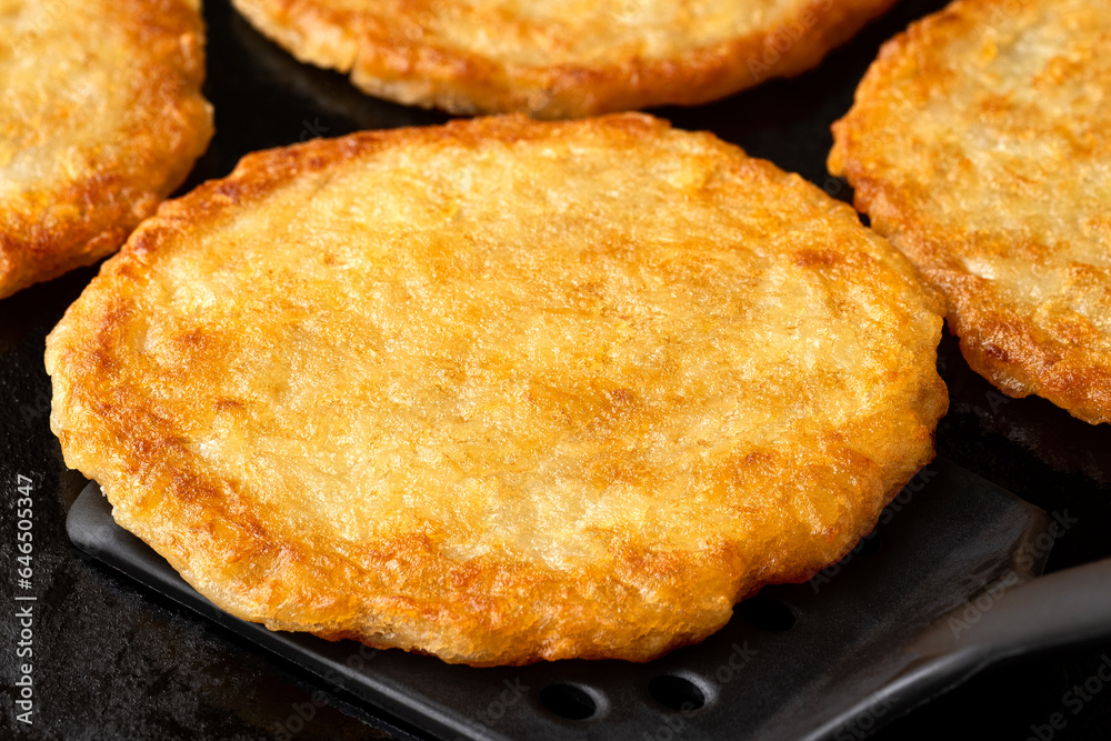 Detail of potato pancakes on cast iron frying pan with black spatula. Detail of potato pancakes on cast iron frying pan with black spatula.