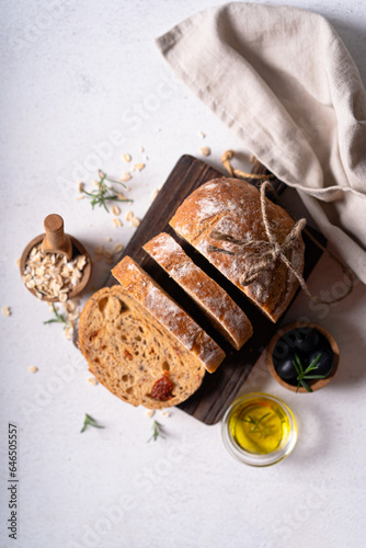 Homemade sourdough ciabatta slice bread with olives and rosemary on a white abstract table. Artisan bread