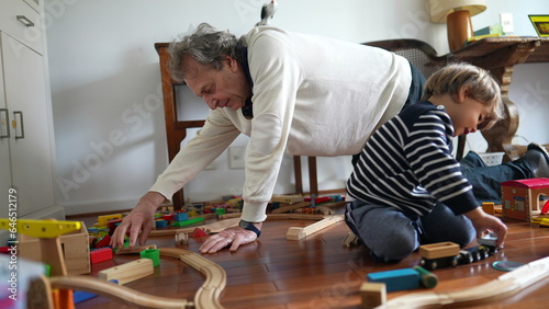 Grandfather and Grandson Constructing Train Tracks on Hardwood Floor, Elderly Man and Young Boy Building Train Set on Wooden Floor