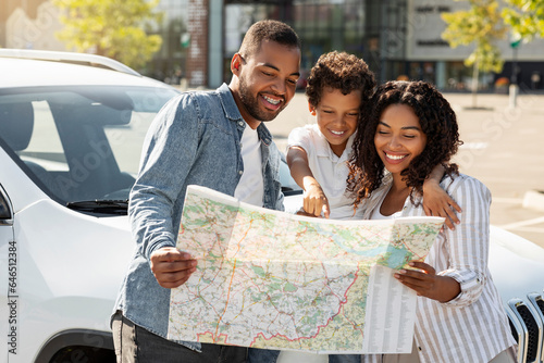 Loving african american family going car trip, checking map