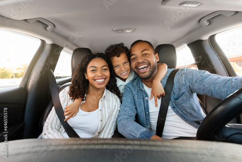 Cheerful loving black family posing in car, going vacation