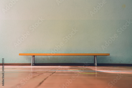 Yellow wooden old bench standing on floor indoor of medical rehabilitation center inside with empty concrete wall with copy space