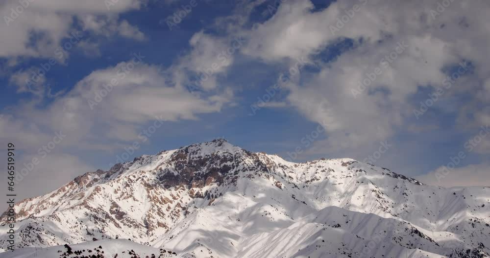 Winter mountains in snowy timelapse. Blue clouds fly over the snow-covered peak. Sun brightly shines in white snow. Cinematic video for background. Atmosphere of amazing nature, breathtaking Winter mountains in snowy timelapse. Blue clouds fly over the snow-covered peak. Sun brightly shines in white snow. Cinematic video for background. Atmosphere of amazing nature, breathtaking
