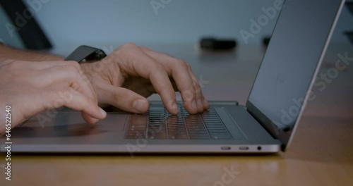 Close-up: hands type and scroll on a trackpad with a laptop