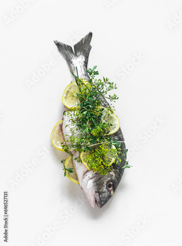 Fresh raw dorada with lemon, fennel, thyme on a light background, top view. Cooking delicious food photo