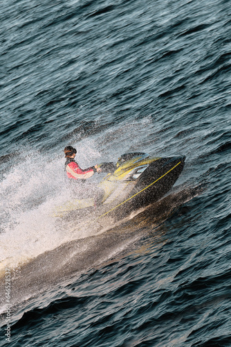 The girl floats on a jet ski on the sea, splashes from the water.