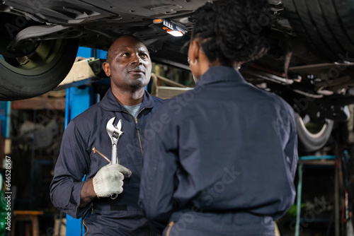 African mechanics checking and fixing underneath car in automobile repair shop © offsuperphoto