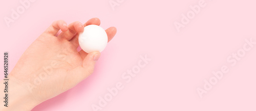 Banner with hand hold ball for ping pong on a pink background. Selective focus.