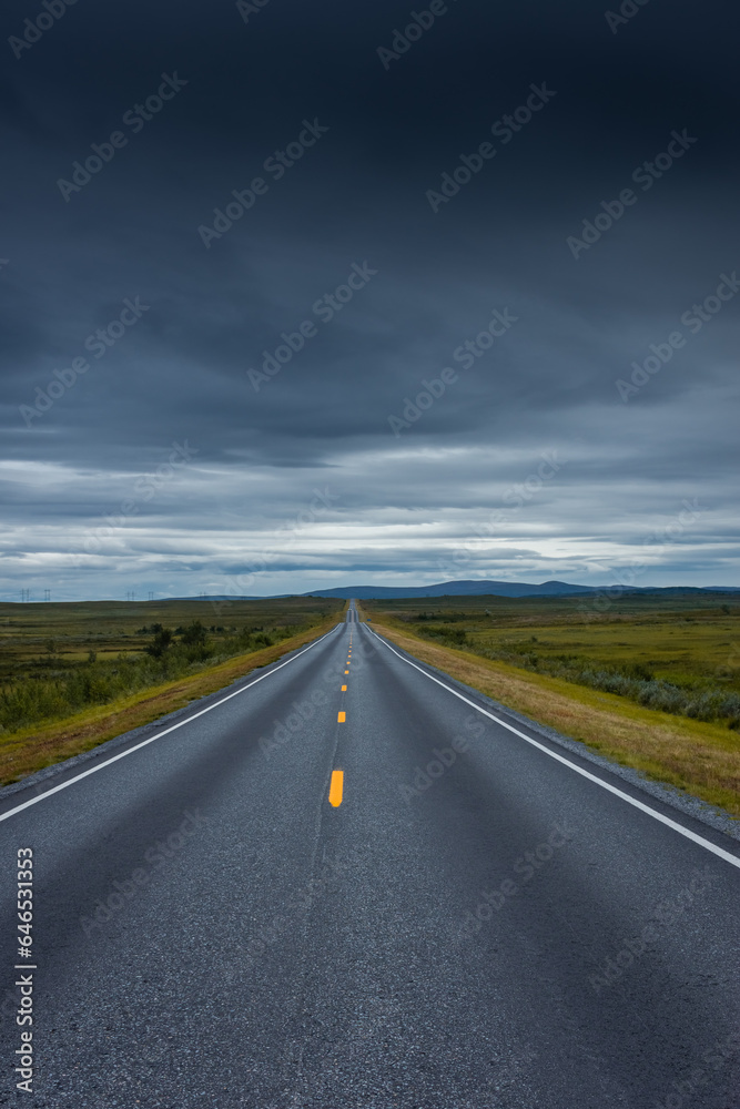 Epic cloudy landscape of an empty highway through the tundra of  Norway