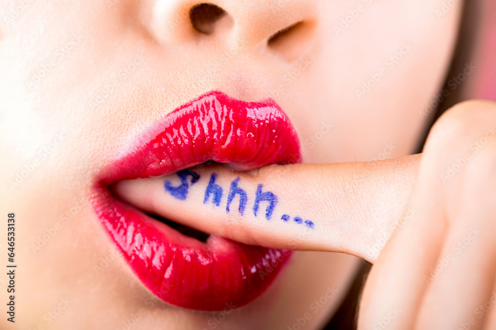 Fototapeta premium Female with finger in mouth. Plump sexy full lips. Purple lipstick. Perfect natural lip makeup. Close-up beautiful lips. Sexy plump lips nude lipstick. Shh. Women's secrets