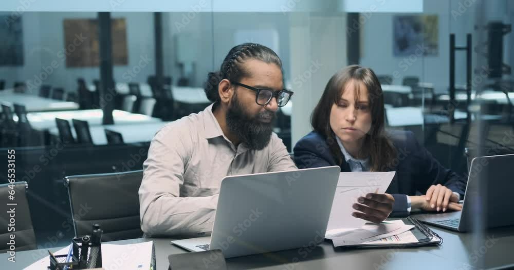 An Indian and a Caucasian manager collaborate on tasks. Their shared dedication to their responsibilities underscores the effectiveness of teamwork transcending cultural backgrounds.