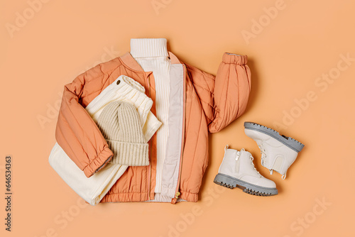 Stylish terracotta children's autumn jacket with knitted sweater, trousers and boots. Fashion kids outfit for for spring, autumn or winter. Flat lay, top view. Clothes set.