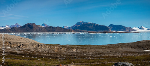 Landing on the shores of the spectacular Kongsfjorden, Spitsbergen, Svalbard, Norway. In the background on the left, the iconic three crown mountain (Tree Kroner) peaks photo