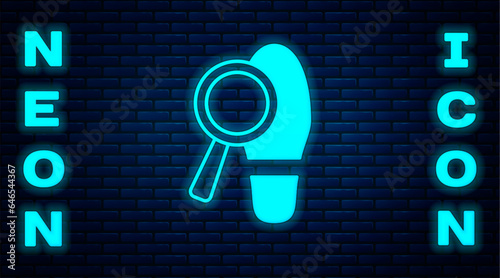 Glowing neon Magnifying glass with footsteps icon isolated on brick wall background. Detective is investigating. To follow in the footsteps. Vector
