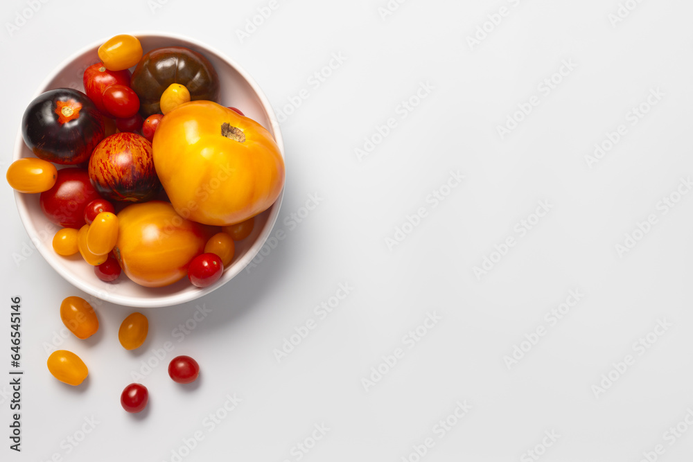 Colorful yellow, red, black tomatoes in a white plate on white background, top view Colorful yellow, red, black tomatoes in a white plate on white background, top view