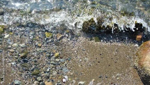 Seashore closeup. Calm ocean water waves splashing on rocky beach. Top view photo